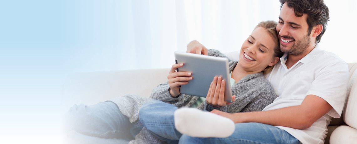Paar sitzt auf dem Sofa und ließt gemeinsam die digital Zeitung auf Ihrem neuen iPad